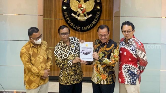 Ketua Komnas HAM Ahmad Taufan Damanik (kedua kanan) saat menyerahkan laporan Komnas HAM terkait Tragedi Kanjuruhan kepada Menkopolhukam Mahfud MD (kedua kiri) di Kantor Kemenko Polhukam, Jakarta Pusat, Kamis (3/11/2022). [Suara.com/Alfian Winanto]