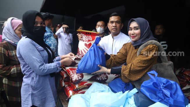 Putra Siregar dan istrinya, Septia Yetri Opani membagikan beras ke warga  di Jakarta, Jumat (4/11). [Suara.com/Oke Atmaja]