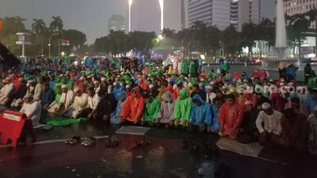 Penampakan massa GNPR menggelar salat Magrib berjemaah di kawasan Patung Kuda, Jakarta. (Suara.com/Rakha)