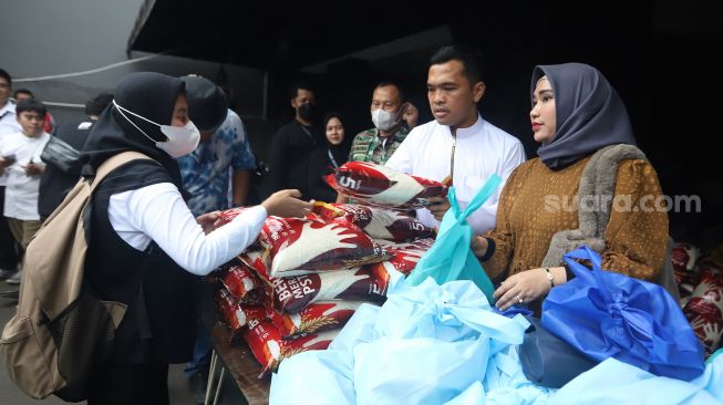 Putra Siregar dan istrinya, Septia Yetri Opani membagikan beras ke warga  di Jakarta, Jumat (4/11). [Suara.com/Oke Atmaja]