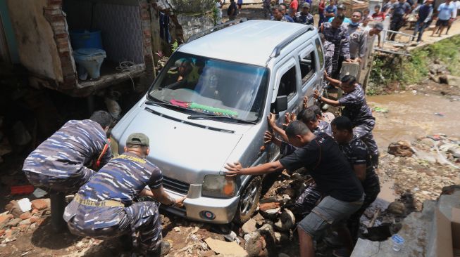 Prajurit TNI AL bersama warga mengevakuasi mobil yang terseret banjir di Kalibaru, Banyuwangi, Jawa Timur, Jumat (4/11/2022). [ANTARA FOTO/Budi Candra Setya].