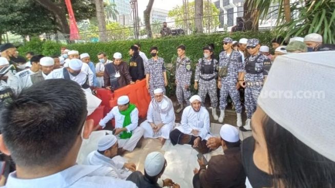 Menantu Habib Rizieq Shihab (HRS), Habib Husein Alatas dan peserta Aksi 411 duduk di atas tikar lalu melantunkan shalawat bersama-sama, Jakarta, Jumat (4/11/2022). [Suara.com/Rakha Arlyanto]