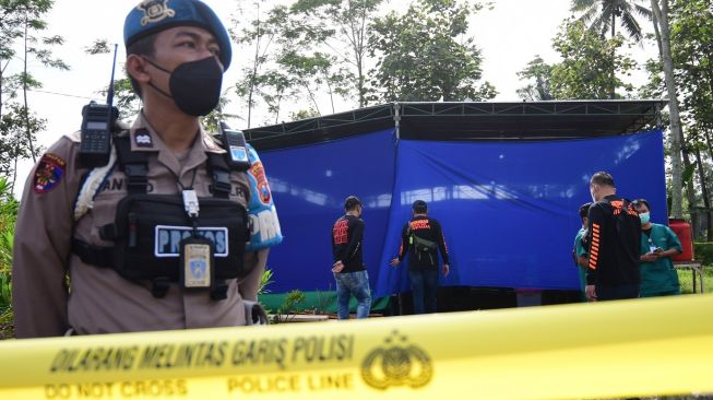 Polisi berjaga di lokasi ekshumas jenazah korban Tragedi Kanjuruhan di Tempat Pemakaman Umum (TPU) Desa Sukolilo, Kecamatan Wajak, Malang, Jawa Timur, Sabtu (5/11/2022). [ANTARA FOTO/Purnomo/abs/YU]