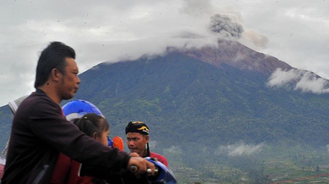 
Pengendara melintas saat Gunung Kerinci mengembuskan gas dan material ke udara yang terlihat dari Kayu Aro, Kerinci, Jambi, Sabtu (5/11/2022). ANTARA FOTO/Wahdi Septiawan