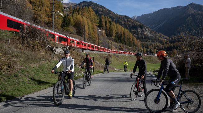 Para pesepda melihat kereta api sepanjang 1910 meter dengan 100 gerbong saat melintas di dekat Bergun, Swiss, Sabtu (29/10/2022). [Fabrice COFFRINI / AFP]