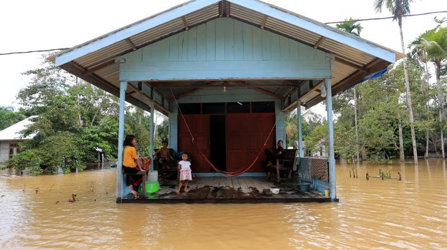 Orang tua bersama anak-anaknya berada di depan rumahnya yang terendam banjir di Desa Napai, Woyla Barat, Aceh Barat, Aceh, Sabtu (5/11/2022). [ANTARA FOTO/Syifa Yulinnas/wsj]
