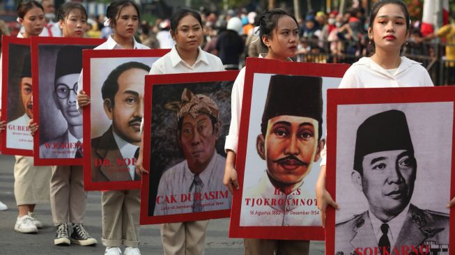 Peserta membawa foto-foto Pahlawan Nasional saat Parade Surabaya Juang di Surabaya, Jawa Timur, Minggu (6/11/2022). [ANTARA FOTO/Didik Suhartono/foc]