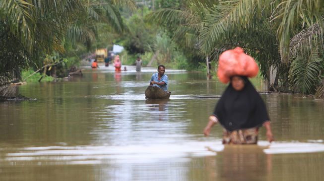 Sejumlah warga melintasi banjir yang merendam Desa Napai, Woyla Barat, Aceh Barat, Aceh, Sabtu (5/11/2022). [ANTARA FOTO/Syifa Yulinnas/wsj]
