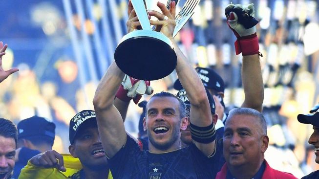 Gareth Bale mengangkat trofi juara Piala MLS 2022. Dia jadi pahlawan usai mencetak gol pada menit ke 120+8' untuk membawa Los Angeles FC menyamakan kedudukan 3-3 atas Philadelphia Union dalam laga final Piala MLS 2022 di Bane of California Stadium, Minggu (6/11/2022) dini hari WIB. LAFC jadi juara usai menang adu penalti 3-0. [Twitter/@LAFC/@GarethBale11]