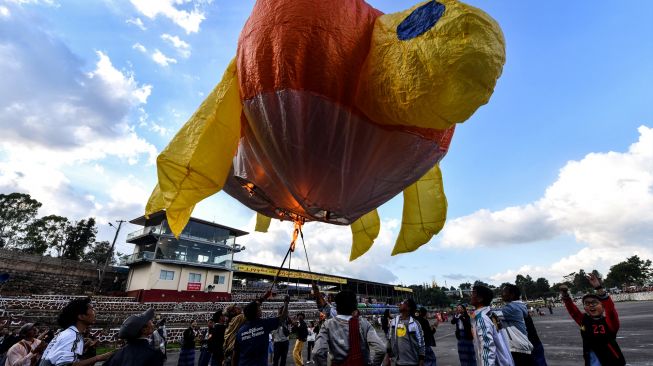 Orang-orang bersiap untuk melepaskan balon udara panas berbentuk kura-kura selama Festival Cahaya Tazaungdaing di Pyin Oo Lwin, Mandalay, Myanmar, Minggu (6/11/2022). [AFP]
