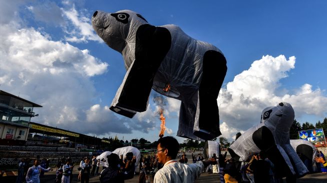 Orang-orang bersiap untuk melepaskan balon udara panas berbentuk beruang kutub selama Festival Cahaya Tazaungdaing di Pyin Oo Lwin, Mandalay, Myanmar, Minggu (6/11/2022). [AFP]
