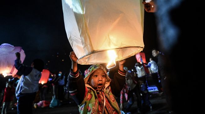 Seorang anak laki-laki melepaskan balon udara panas kecil selama Festival Cahaya Tazaungdaing di Pyin Oo Lwin, Mandalay, Myanmar, Minggu (6/11/2022). [AFP]