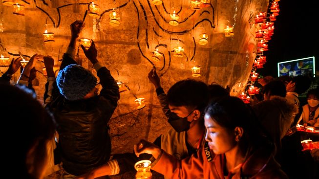 Orang-orang yang mempersiapkan lentera untuk dipasang pada balon udara selama Festival Cahaya Tazaungdaing di Pyin Oo Lwin, Mandalay, Myanmar, Minggu (6/11/2022). [AFP]
