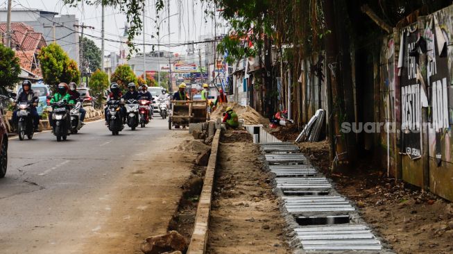 Pekerja menyelesaikan proyek revitalisasi trotoar di Jalan Dewi Sartika, Depok, Jawa barat, Rabu (9/11/2022). [Suara.com/Alfian Winanto]