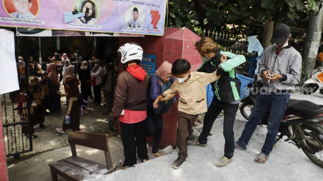 Sejumlah siswa berjalan keluar melintasi jalan darurat yang dibuat pihak orang tua murid di SDN Pondok Cina 1, Depok, Jawa Barat, Rabu (9/11/2022). [Suara.com/Alfian Winanto]