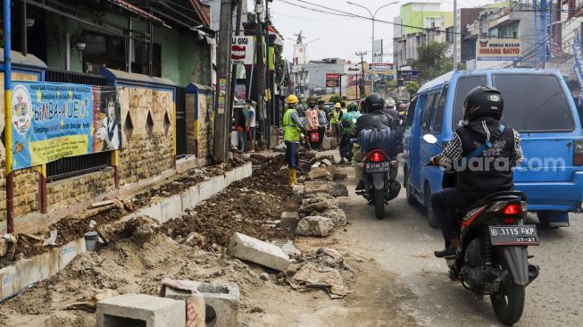 Pekerja menyelesaikan proyek revitalisasi trotoar di Jalan Dewi Sartika, Depok, Jawa barat, Rabu (9/11/2022). [Suara.com/Alfian Winanto]