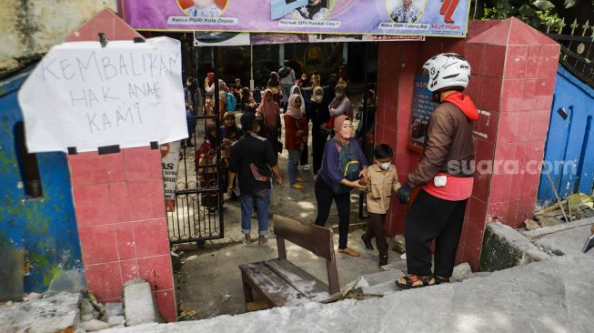 Sejumlah siswa berjalan keluar melintasi jalan darurat yang dibuat pihak orang tua murid di SDN Pondok Cina 1, Depok, Jawa Barat, Rabu (9/11/2022). [Suara.com/Alfian Winanto]