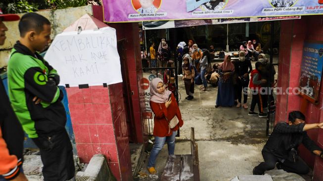 Sejumlah orang tua murid melihat kondisi SDN Pondok Cina 1 yang tertutup trotoar di Depok, Jawa Barat, Rabu (9/11/2022). [Suara.com/Alfian Winanto]