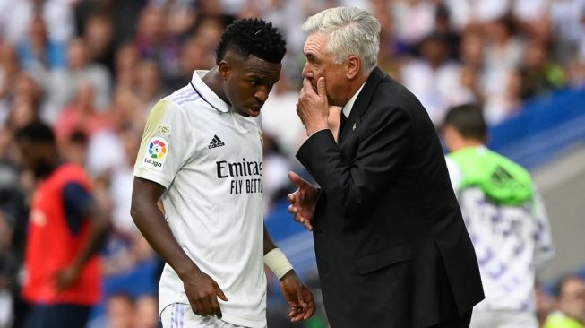 Pelatih Real Madrid, Carlo Ancelotti (kanan) memberikan instruksi pada penyerang sayap Vinicius Junior. [PIERRE-PHILIPPE MARCOU / AFP]