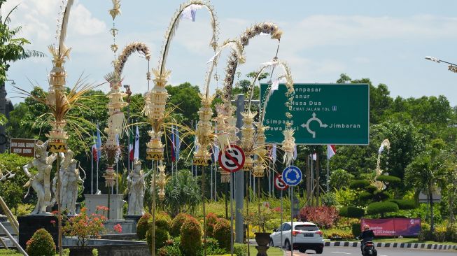 Kendaraan melintas di jalan yang pinggirnya dihiasi penjor atau hiasan janur kuning khas Bali di Jalan Bandara Ngurah Rai, Kabupaten Badung, Bali, Kamis (10/11/2022). [ANTARA FOTO/Aditya Pradana Putra/nym].