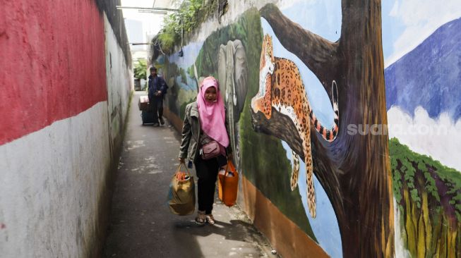 Warga melintas di gang Satria, Mampang, Jakarta Selatan, Kamis (10/11/2022). [Suara.com/Alfian Winanto]