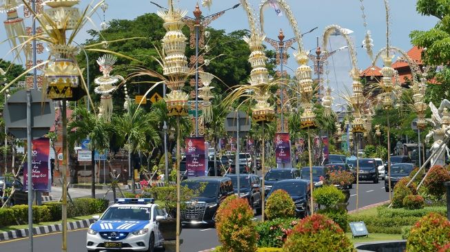 Kendaraan melintas di jalan yang pinggirnya dihiasi penjor atau hiasan janur kuning khas Bali di Jalan Bandara Ngurah Rai, Kabupaten Badung, Bali, Kamis (10/11/2022). [ANTARA FOTO/Aditya Pradana Putra/nym].