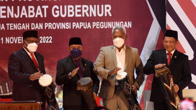 Mendagri Tito Karnavian (kanan) didampingi Wamendagri John Wempi Wetipo (kiri) dan anggota Komisi II DPR yang juga mantan Ketua Pansus Revisi UU Otonomi Khusus Papua Komarudin Watubun (kedua kanan) memukul tifa saat peresmian tiga daerah otonom baru papua dan pelantikan Penjabat Gubernur Provinsi Papua Selatan, Papua Tengah, dan Papua Pegunungan di Kantor Kemendagri, Jakarta, Jumat (11/11/2022). [ANTARA FOTO/Indrianto Eko Suwarso/nz]