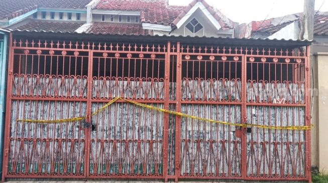 Pagar rumah satu keluarga tewas membusuk di Kalideres, Jakarta Barat, dipasang garis polisi, Sabtu (12/11/2022). [Suara.com/Yosea Arga Pramudita]