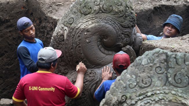 Arkeolog dari Badan Riset dan Inovasi Nasional (BRIN) dibantu pekerja membersihkan arca saat ekskavasi di Situs Adan-adan, Desa Adan-adan, Kediri, Jawa Timur, Sabtu (12/11/2022). [ANTARA FOTO/Prasetia Fauzani/tom]