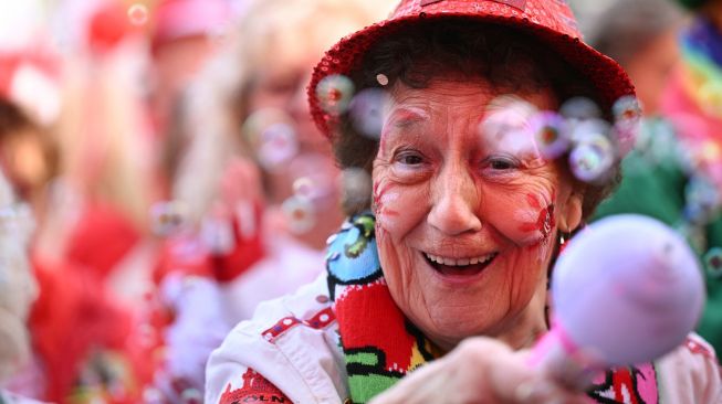 Seorang pengunjung merayakan dimulainya musim Karnaval musim karnaval "kelima" atau karnaval konyol di Cologne, Jerman, Jumat (11/11/2022). [INA FASSBENDER / AFP]