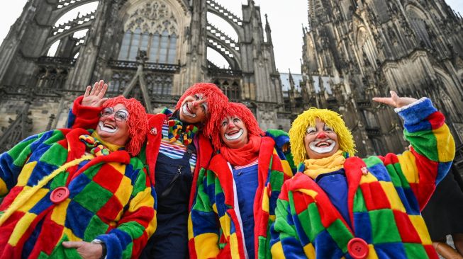 Orang-orang berswafoto di depan katedral untuk merayakan dimulainya musim Karnaval musim karnaval "kelima" atau karnaval konyol di Cologne, Jerman, Jumat (11/11/2022). [INA FASSBENDER / AFP]