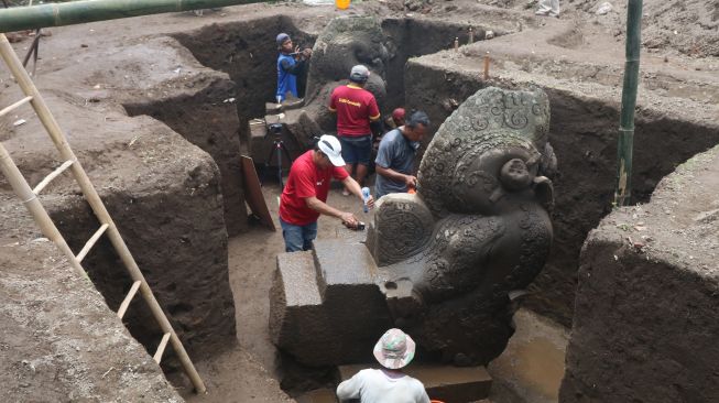 Arkeolog dari Badan Riset dan Inovasi Nasional (BRIN) dibantu pekerja membersihkan arca saat ekskavasi di Situs Adan-adan, Desa Adan-adan, Kediri, Jawa Timur, Sabtu (12/11/2022). [ANTARA FOTO/Prasetia Fauzani/tom]