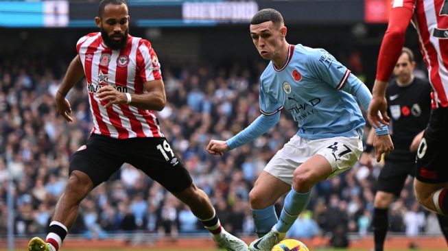 Gelandang Manchester City Phil Foden (kanan) bersaing dengan gelandang Brentford Bryan Mbeumo (kiri) saat pertandingan sepak bola Liga Premier Inggris antara Manchester City dan Brentford di Stadion Etihad, Manchester, Inggris, Sabtu (12/11/2022). [Oli SCARFF / AFP]