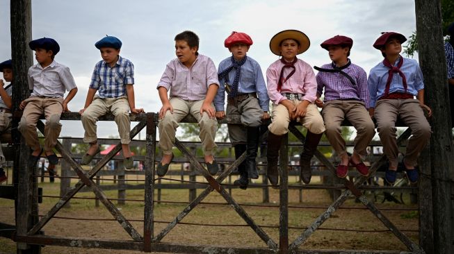 Para Gaucho cilik melihat pertunjukkan rodeo selama "Hari Tradisi Gaucho ke-83" di San Antonio de Areco, Argentina, Sabtu (12/11/2022). [Luis ROBAYO / AFP]