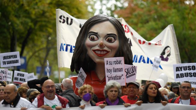 Para pengunjuk rasa membawa patung yang menggambarkan presiden daerah Isabel Diaz Ayuso selama demonstrasi yang diserukan untuk perbaikan sistem kesehatan di Madrid, Spanyol, Minggu (13/11/2022). [OSCAR DEL POZO / AFP]
