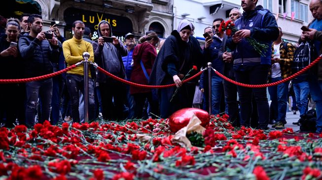 Orang-orang meletakkan bunga di tugu peringatan darurat untuk para korban di lokasi ledakan bom di Jalan Istiklal, Istanbul, Turki, Senin (14/11/2022). [Yasin AKGUL/AFP]