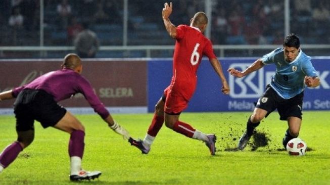 Pemain Uruguay Luis Suarez dijatuhkan Nova Arianto saat berusaha menjebol gawang Indonesia yang dikawal Markus Horison dalam pertandingan persahabatan di SUGBK, Jakarta, pada 8 Oktober 2010. [AFP] 