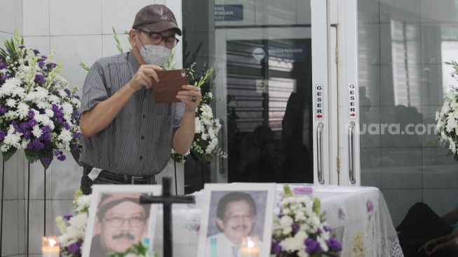 Aktor Ray Sahetapy memotret  peti jenazah Rudi Salam, Jakarta, Jumat (18/11). [Suara.com/Oke Atmaja]