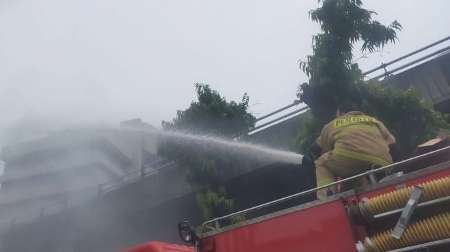 Petugas dari Suku Dinas Penanggulangan Kebakaran dan Penyelamatan Jakarta Barat, saat berupaya memedamkan api yang meludeskan puluhan kios di Pasar Pagi, Jalan Asemka Taman Sari Jakarta Barat, pada Jumat (18/11/2022). [Foto dok. Damkar]