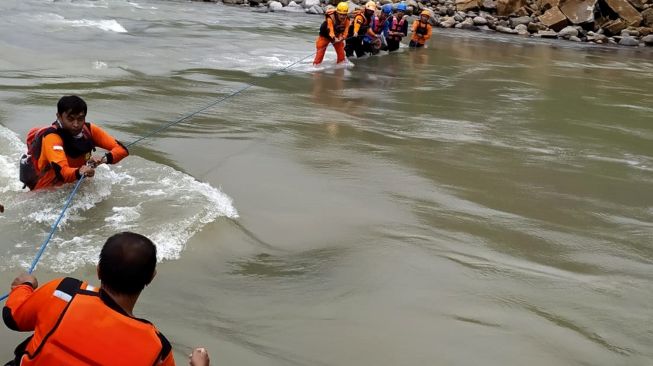 Sejumlah petugas SAR gabungan menyeberangi sungai saat mencari korban tanah longsor di Desa Lonjoboko, Kabupaten Gowa, Sulawesi Selatan, Jumat (18/11/2022).[ANTARA FOTO/BASARNAS]