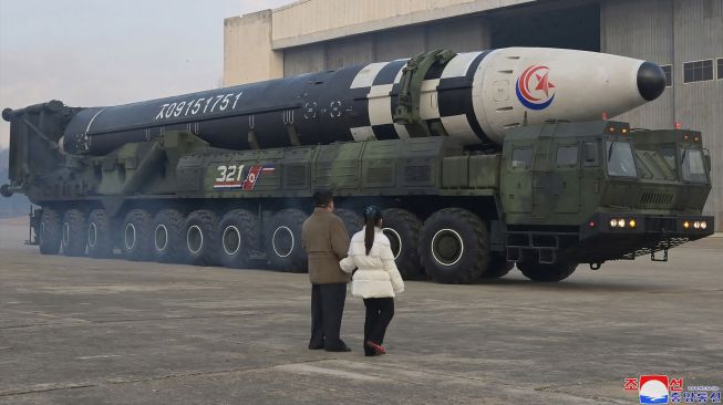 Pemimpin Korea Utara Kim Jong Un (kanan) berjalan dengan putrinya saat dia memeriksa rudal balistik antarbenua (ICBM) baru "Hwasong Gun 17" di Bandara Internasional Pyongyang, Korea Utara, Jumat (18/11/2022). [KCNA VIA KNS/AFP]