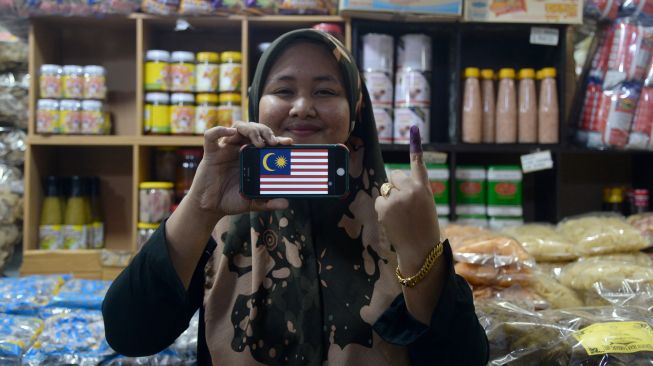 Seorang pedagang menunjukkan jari yang telah dicoblos dakwat di tokonya Pasar Siti Khadijah usai pemungutan suara di Kota Bharu, Kelantan, Malaysia, Sabtu (19/11/2022). [ANTARA FOTO/ Rafiuddin Abdul Rahman/rwa]