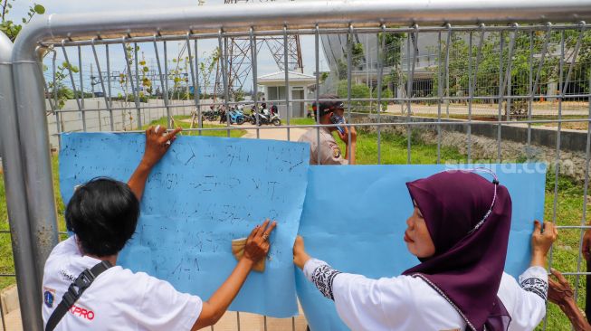 Warga berunjuk rasa di depan gerbang Kampung Susun Bayam, Jakarta Utara, Senin (21/11/2022). [Suara.com/Alfian Winanto]