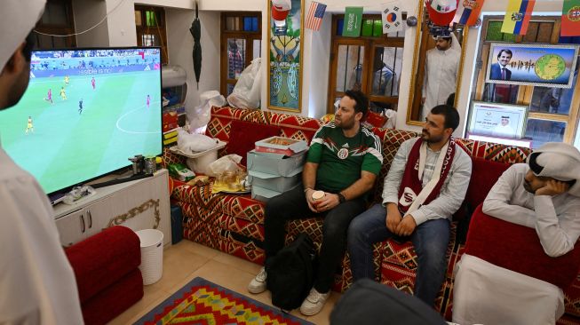 Penggemar sepak bola menyaksikan pembukaan pertandingan sepak bola Grup A Piala Dunia 2022  antara Qatar dan Ekuador di Souq Waqif di Doha, Qatar, Minggu (20/11/2022). [ANDREJ ISAKOVIC / AFP]