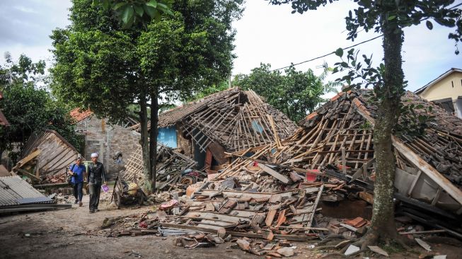 Warga melintas di depan rumah yang roboh akibat gempa di Kampung Selakawung Tengah, Kabupaten Cianjur, Jawa Barat, Selasa (22/11/2022). [ANTARA FOTO/Raisan Al Farisi/foc].