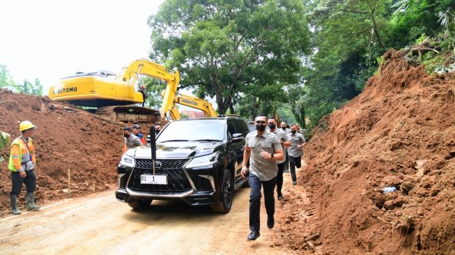 Presiden Joko Widodo atau Jokowi menggunakan mobil Lexus warna hitam saat meninjau lokasi gempa Cianjur, Jawa Barat. Petugas paspampres mengawal dari sisi kiri dan kanan. [Laily Rachev - Biro Pers Sekretariat Presiden]