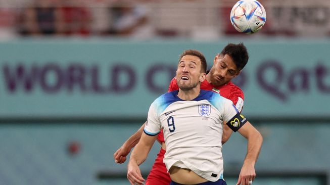 Penyerang Inggris Harry Kane melompat untuk menyundul bola selama pertandingan sepak bola Grup B Piala Dunia 2022 antara Inggris dan Iran di Stadion Internasional Khalifa di Doha, Qatar, Senin (21/11/2022). [ADRIAN DENNIS / AFP]