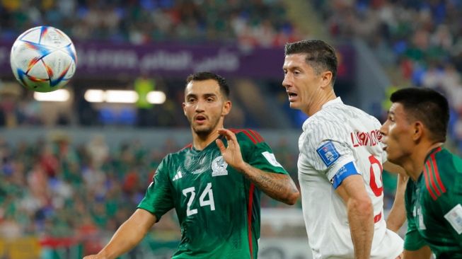 Gelandang Timnas Meksiko #24 Luis Chavez (Kiri) berebut bola dengan penyerang Polandia #09 Robert Lewandowski selama matchday pertama Grup C Piala Dunia 2022 antara Meksiko vs Polandia di Stadion 974 di Doha pada 23 November 2022.Aneh ANDERSEN / AFP.