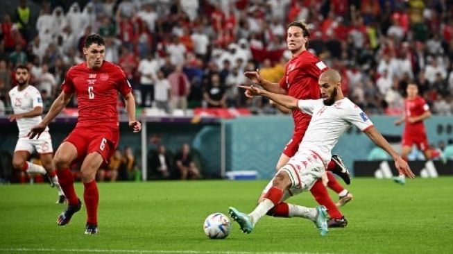 Pemain Denmark Andreas Christensen (kiri) menghalau passing pemain Tunisia Aissa Laidouni dalam pertandingan Grup D Piala Dunia 2022 di Educational City Stadium, Qatar, Selasa (22/11/2022). [AFP]