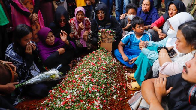 Keluarga dan pelayat berdoa di atas pusara Agung Yulianto alias Ki Joko Bodo di TPU Kober, Lubang Buaya, Jakarta Timur, Selasa (22/11/2022). [Suara.com/Alfian Winanto]